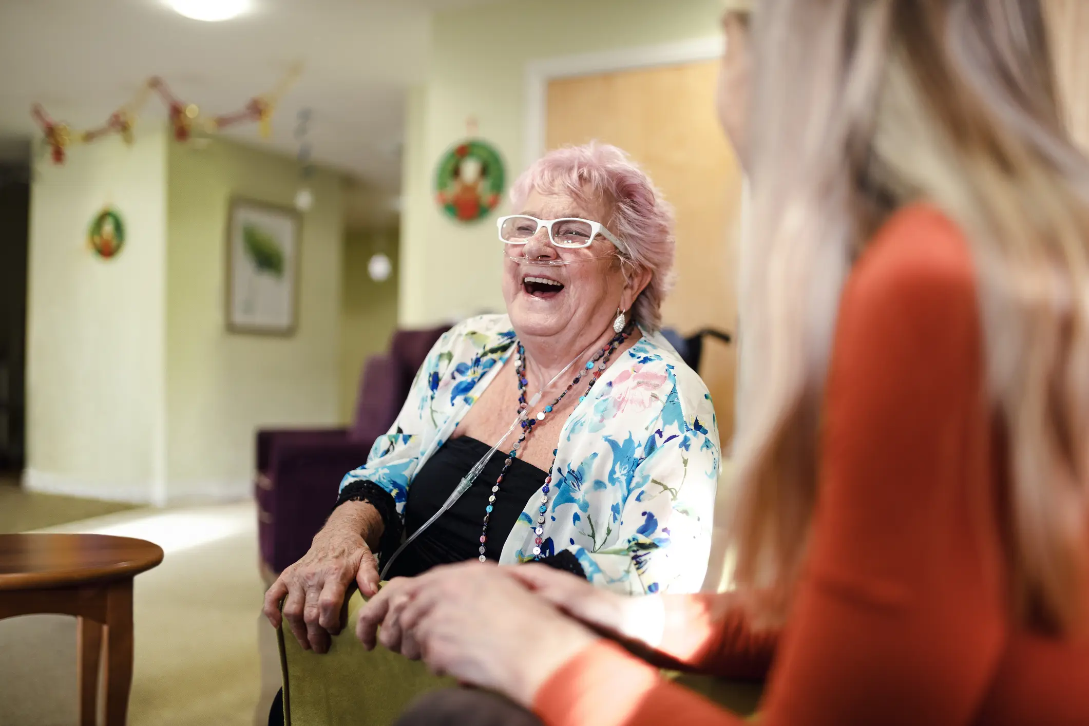 Elderly woman smiling and laughing with caregiver, supporting COPD/emphysema patient treatment and quality of life.