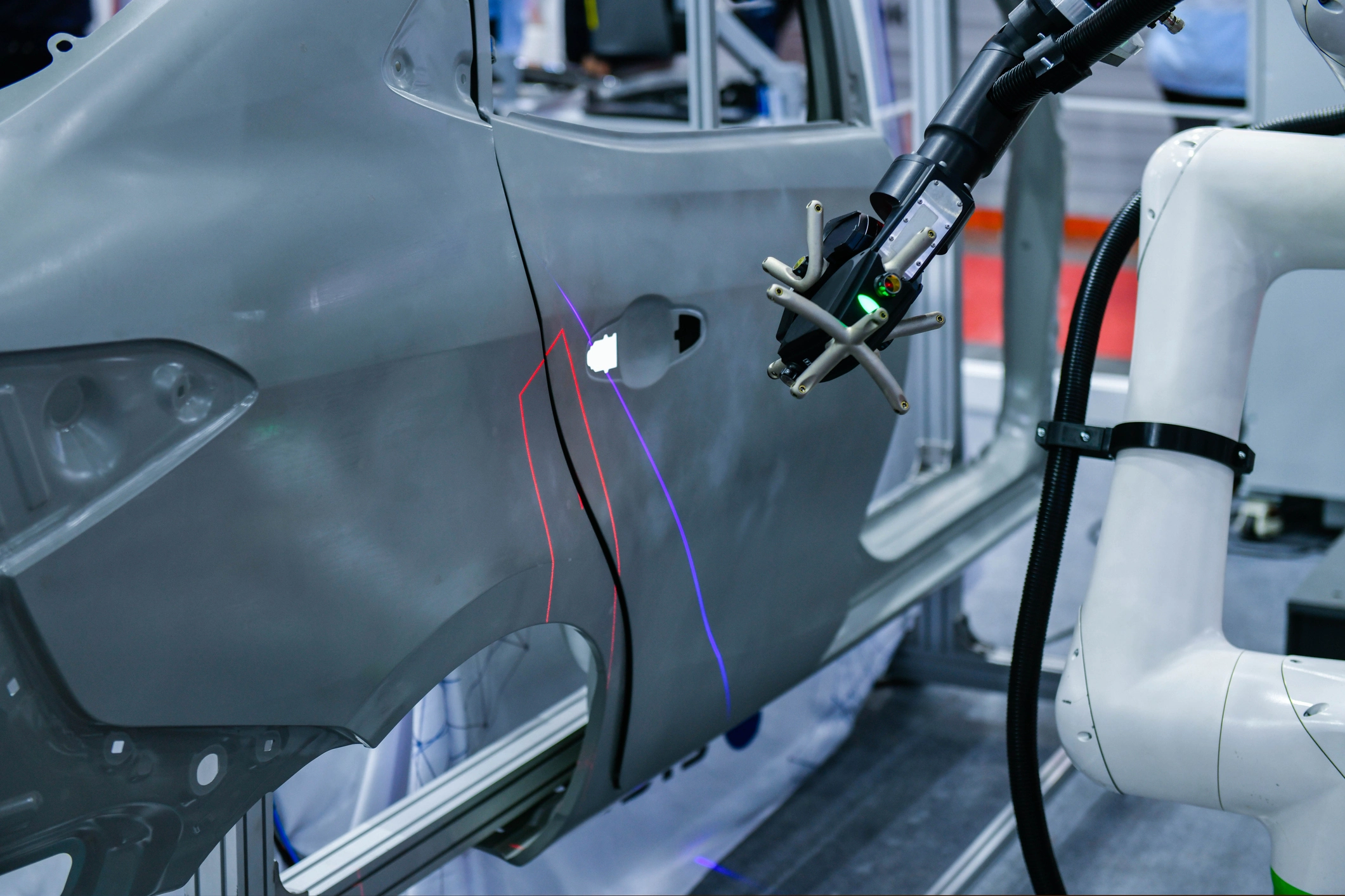 Robotic arm measuring car body panel in automotive manufacturing, demonstrating metrology and inspection technologies.